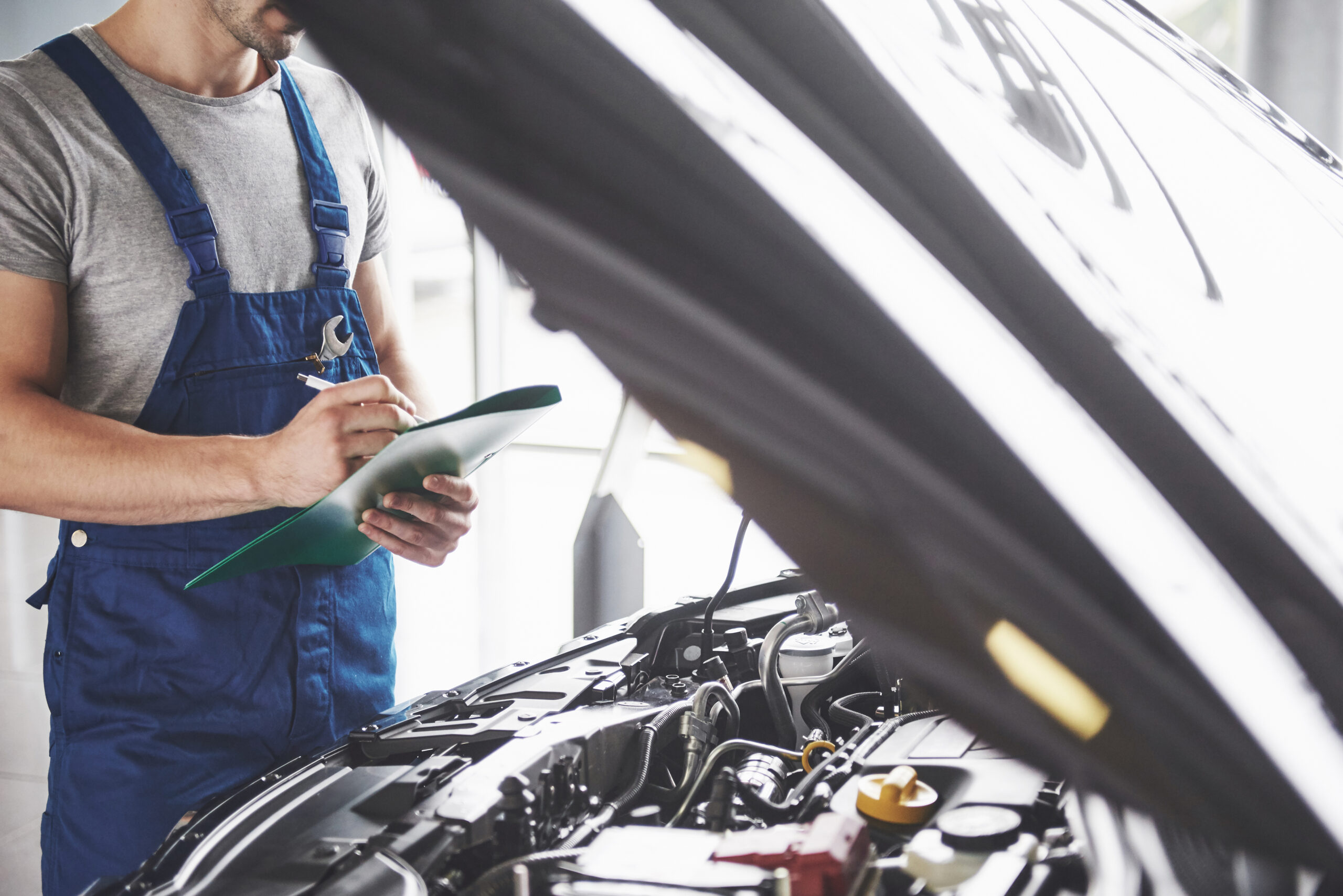 A certified mechanic performing an MOT check on a car at an MOT test center.